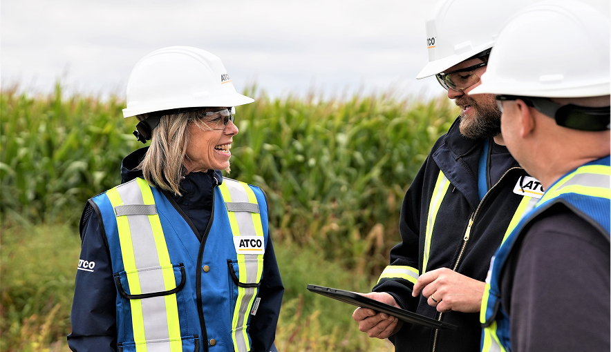 Contractors wearing ATCO safety gear talking in a field